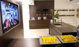 Hier ziet u een voorbeeld ervan, hoe een televisie elegant in een keuken kan worden ingebouwd. Het apparaat zit achter een wand die dezelfde tint heeft als de keukenmeubels. Zuordnung: Stil Design-keukens, Planungsart Open keuken (woonkeuken)