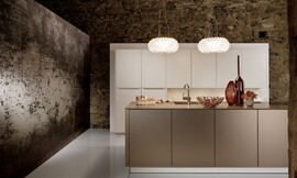 Deze luxe keuken, bestaande uit een hoge keukenwand en een keukeneiland, werkt kalm door de beige en crème-tint. Het ontwerp is symmetrisch en de meubels zijn onverstoord door grepen of versieringen. Zuordnung: Stil Luxe keukens, Planungsart Open keuken (woonkeuken)