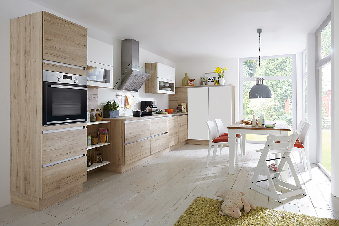 Vriendelijke familiekeuken: deze keuken laat de ruimte in lichte hout-optiek schitteren. Talrijke details zoals regaal-elementen en glasinzetten zorgen voor een moderne look. Zuordnung: Stil Moderne keukens, Planungsart keukenblok